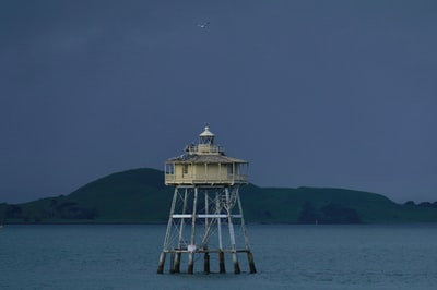 Black and white lighthouse on the water during the day
